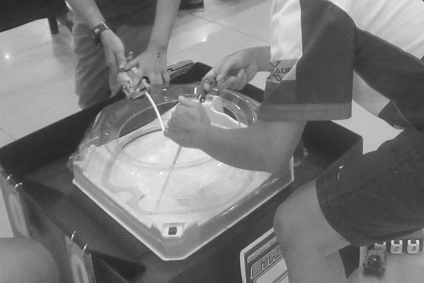 Due giocatori lanciano il loro Beyblade X nella stessa arena trasparente